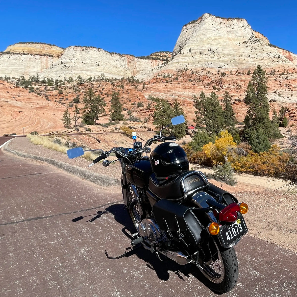 Motorcycle on a road with desert landscape and cliffs in the background
