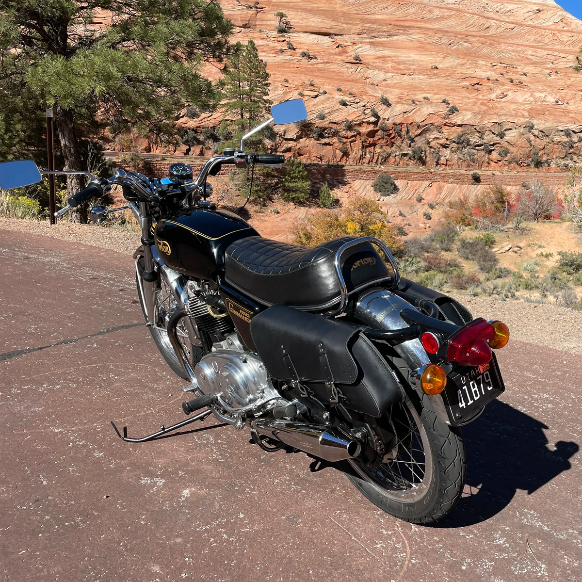 Black motorcycle parked on a road with a scenic background of mountains and trees.